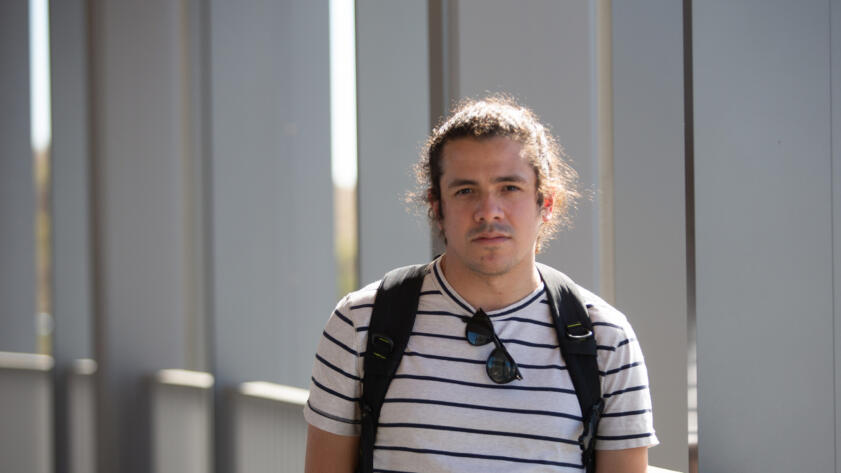 Photo of Eric Natividad, wearing a backpack, looking straight into the camera